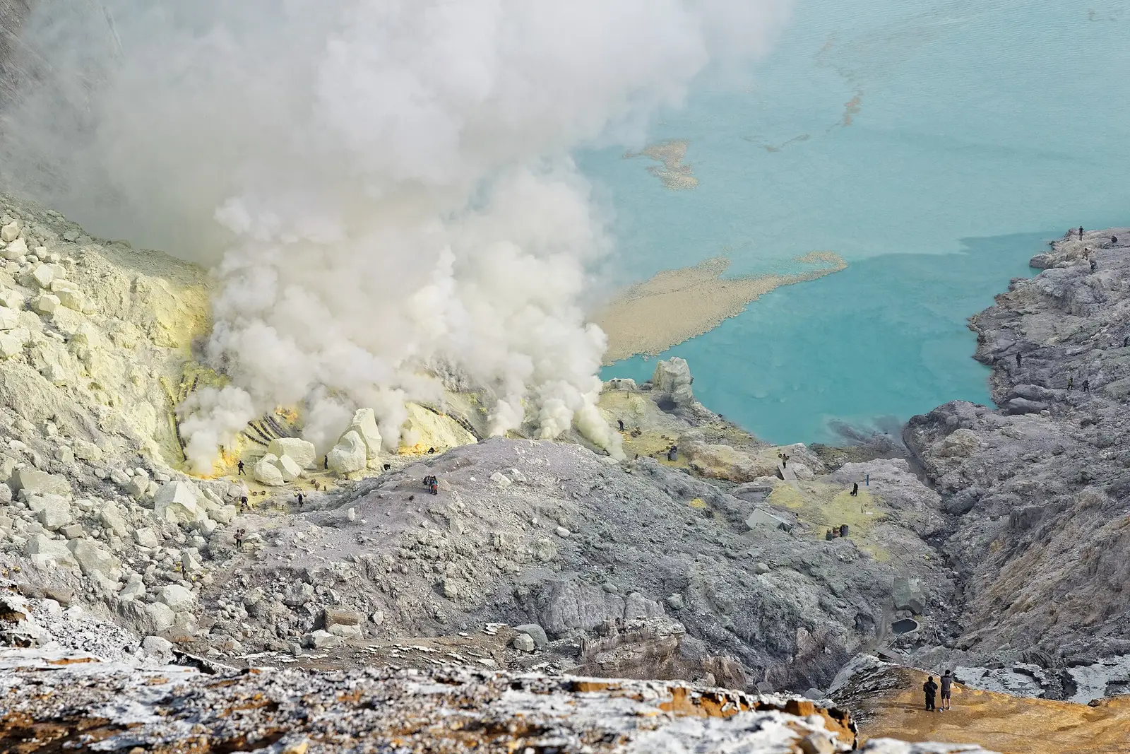 Sulphur smoke over the miners' work area beside the turquoise crater lake, seen from above