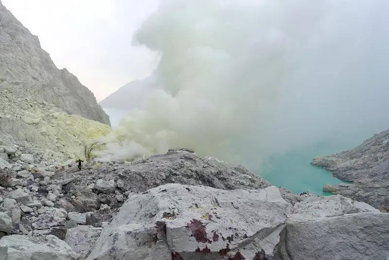 Yellow-white sulphur smoke drifting over the acid lake at dawn, seen from the crater floor