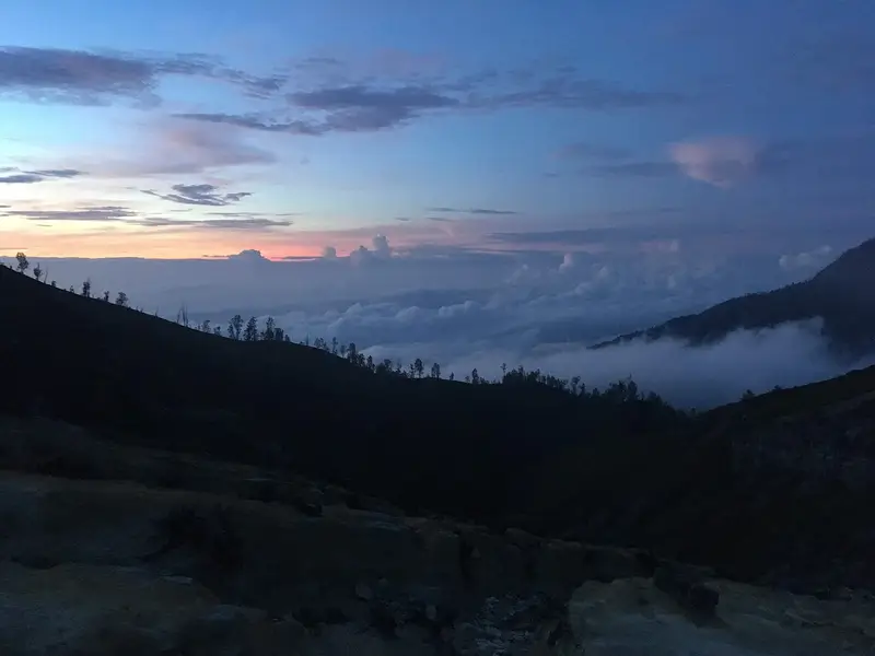 Dawn sky over forested ridges and low cloud seen from Kawah Ijen