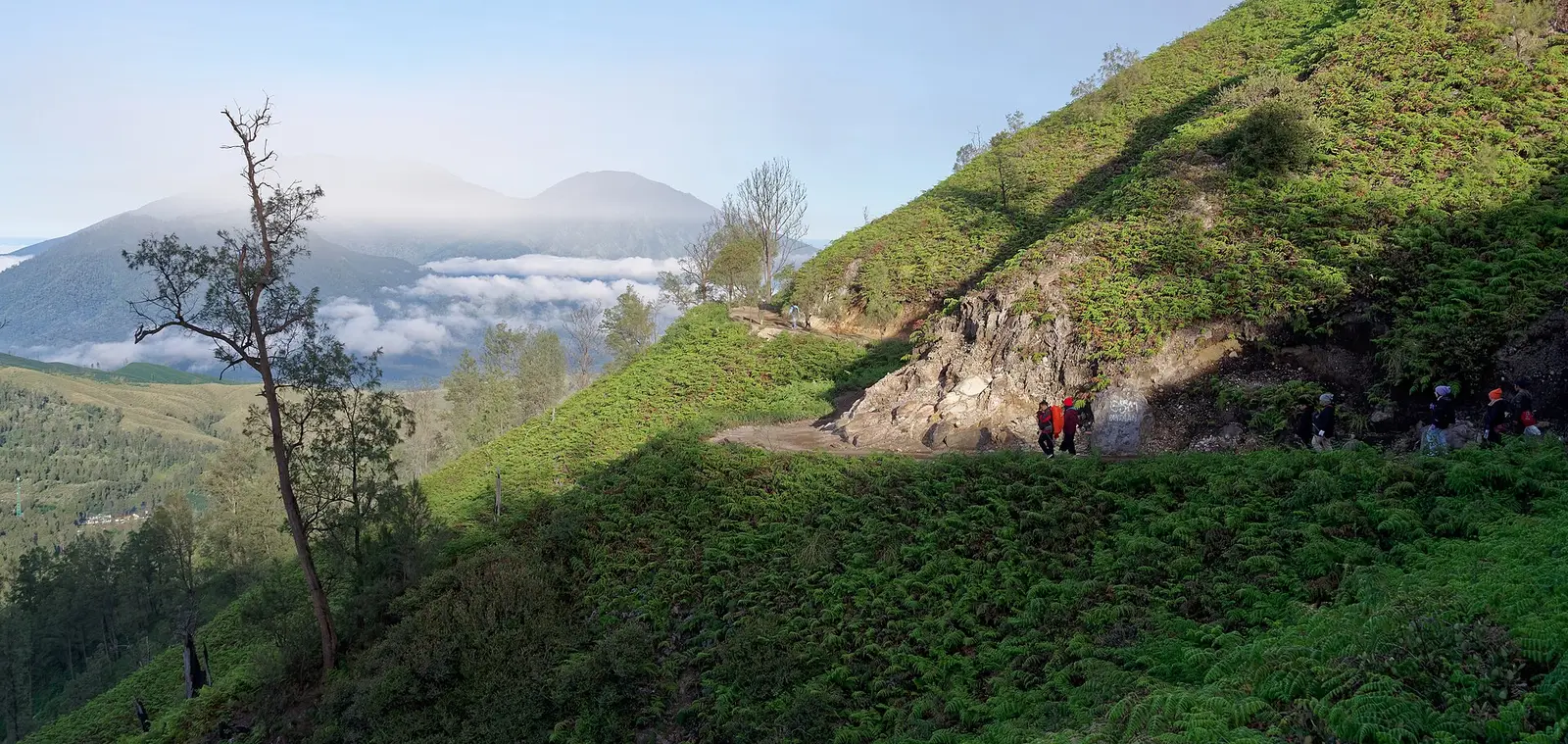 The green hillside trail down from Ijen, with Mount Raung above the clouds on the left